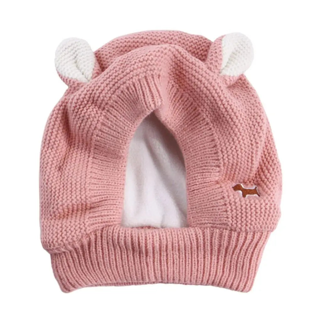 Pink knitted dog hat with white ears.